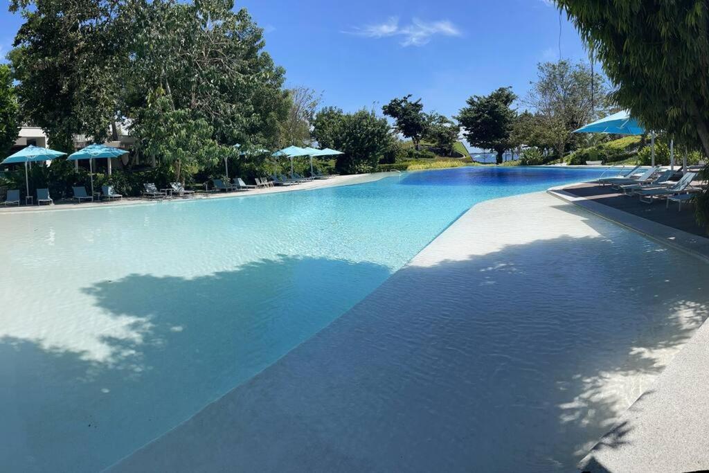 a large swimming pool with blue water and umbrellas at Ma Roberta - Tambuli Resort with fast Wifi 16 Floor Studio Type in Lapu Lapu City