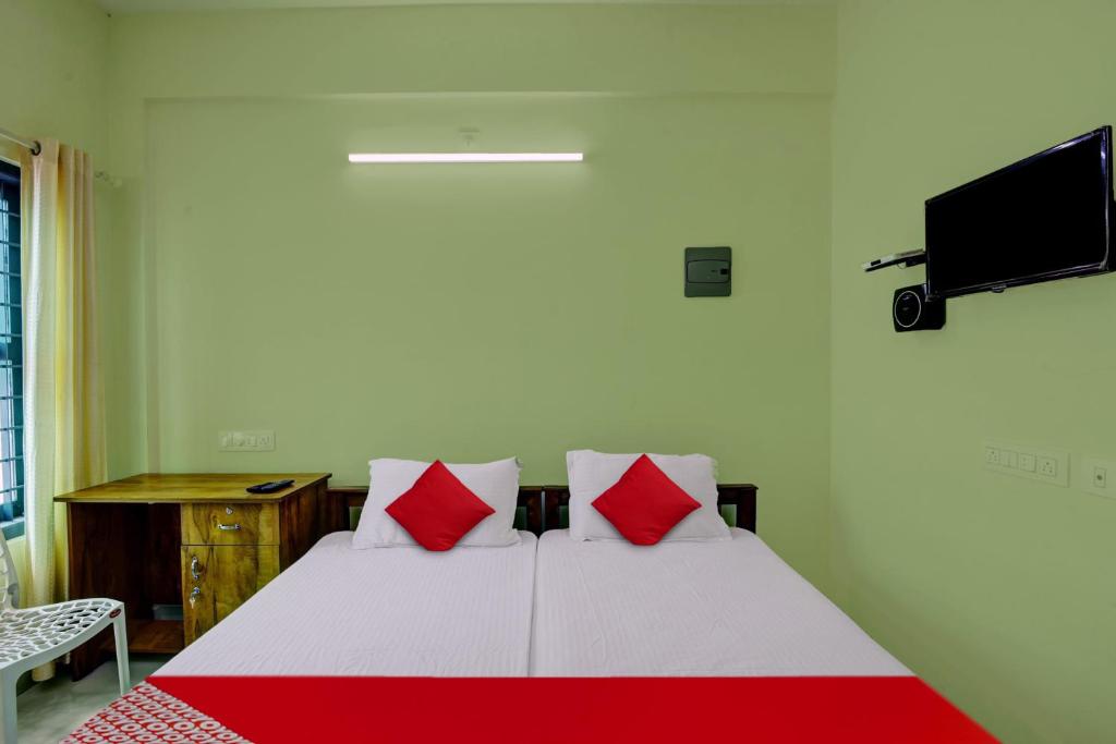 una camera da letto con un letto con cuscini rossi e una TV di OYO Prasanth Holiday Inn a Chegāt