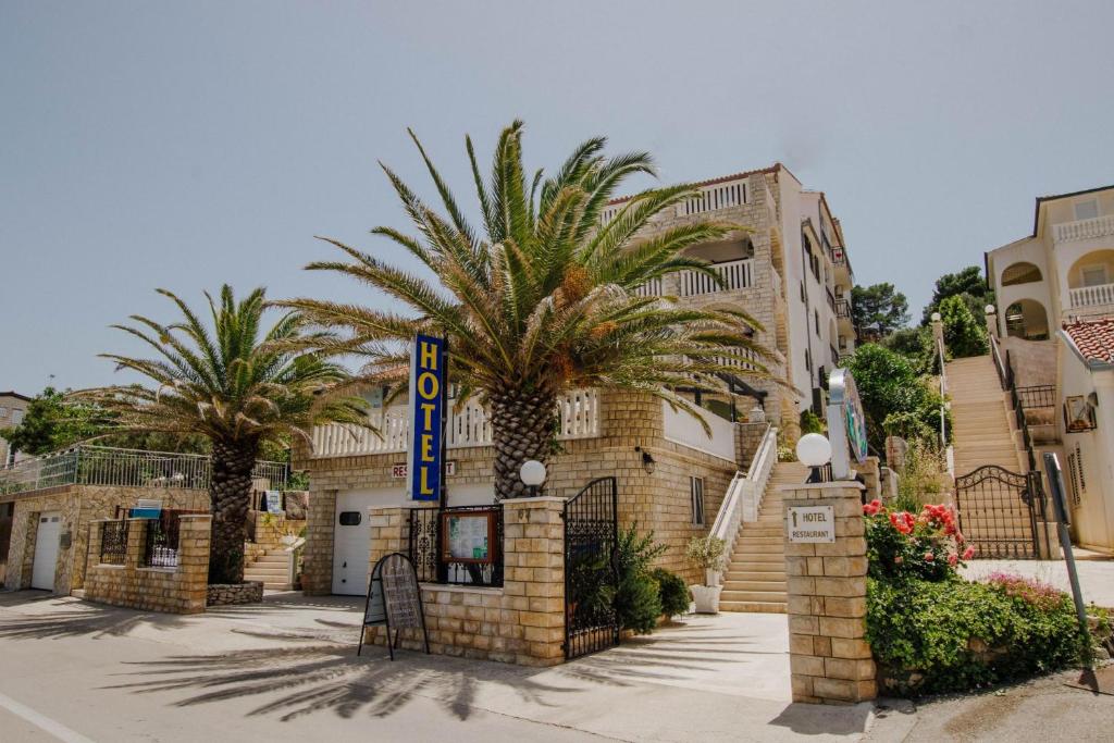 a hotel with palm trees in front of a building at Hotel Vila Tina in Trogir