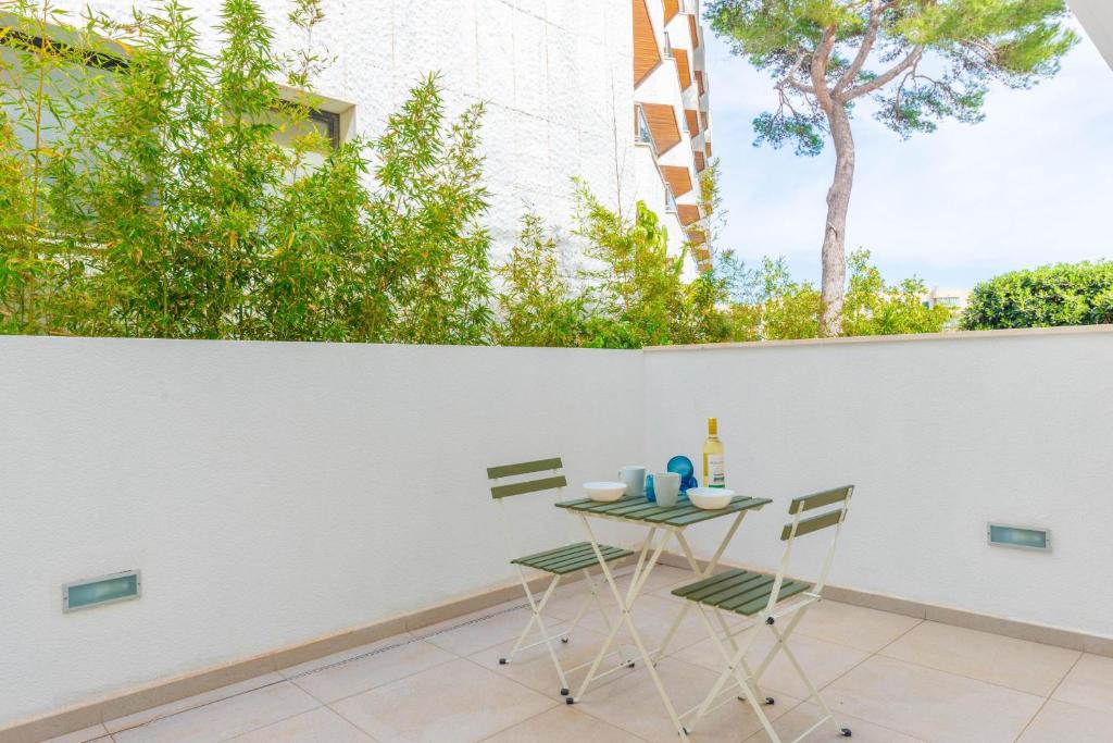 a table and chairs on a patio with a white wall at Aroa 1 in Cala Ratjada