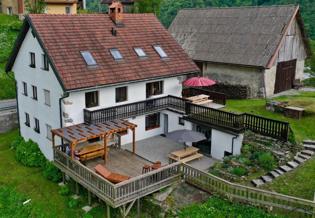 a large white house with a deck with an umbrella at Hisa Brdo Guesthouse in Tolmin