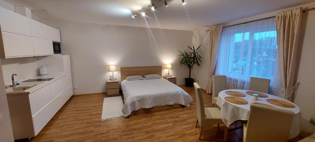 a room with a bed and a kitchen with a table at Apartamentai šalia baseino in Palanga