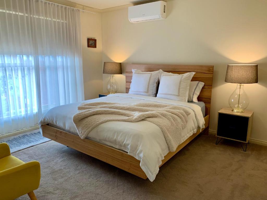 1 dormitorio con 1 cama grande con sábanas y almohadas blancas en Luxury Inner City Townhouse en Bendigo
