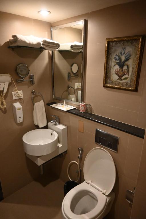 a bathroom with a toilet and a sink and a mirror at SVN GRAND in Kākināda
