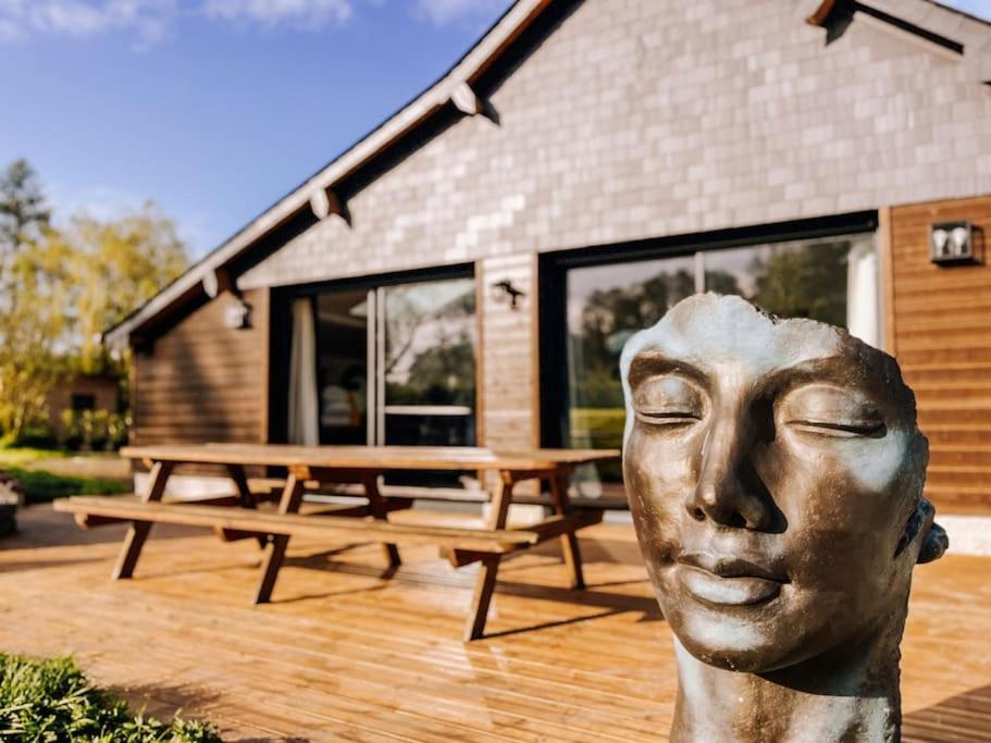 une statue d'une tête devant une table de pique-nique dans l'établissement Domaine de Syrka à Deauville, à Saint-Étienne-la-Thillaye