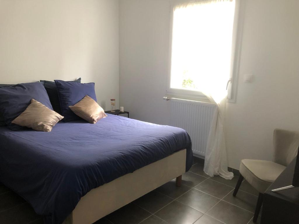 1 dormitorio con cama con sábanas azules y ventana en Autret en Guipavas