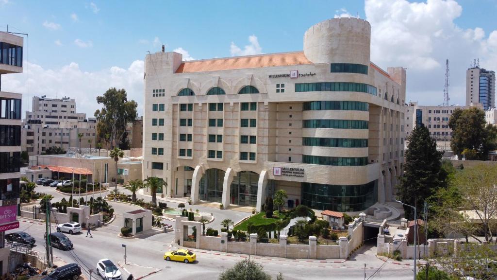 a large building in a city with a parking lot at Millennium Palestine Ramallah in Ramallah