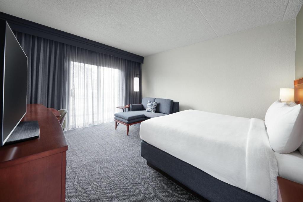 メアリーランド・ハイツにあるCourtyard St. Louis Westport Plazaのベッドとテレビが備わるホテルルームです。