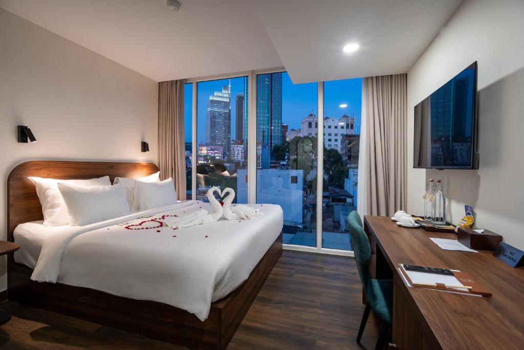 Cette chambre comprend un lit, un bureau et une fenêtre. dans l'établissement Hato Saigon Hotel & Rooftop, à Hô-Chi-Minh-Ville