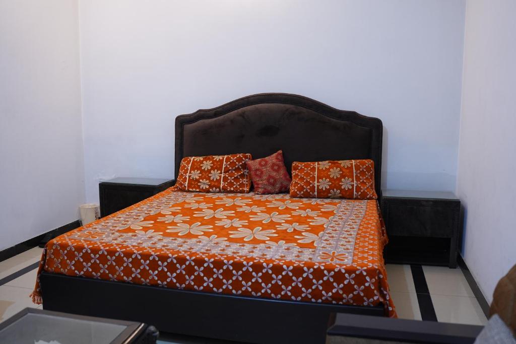 a bed with an orange and white comforter and pillows at Mohal's House in Lahore