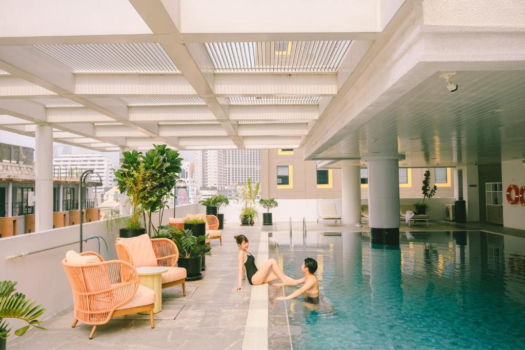 two children playing in a swimming pool in a building at PARKROYAL Suites Bangkok in Bangkok