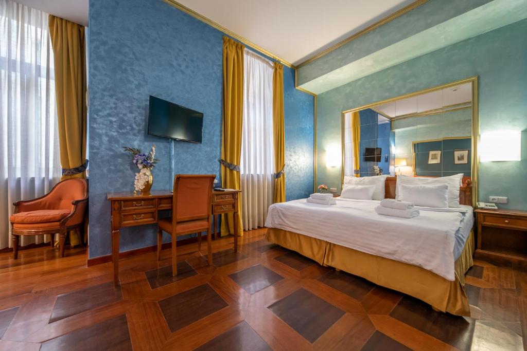 a bedroom with a bed and a desk and a mirror at Hotel Kinsky Fountain in Prague