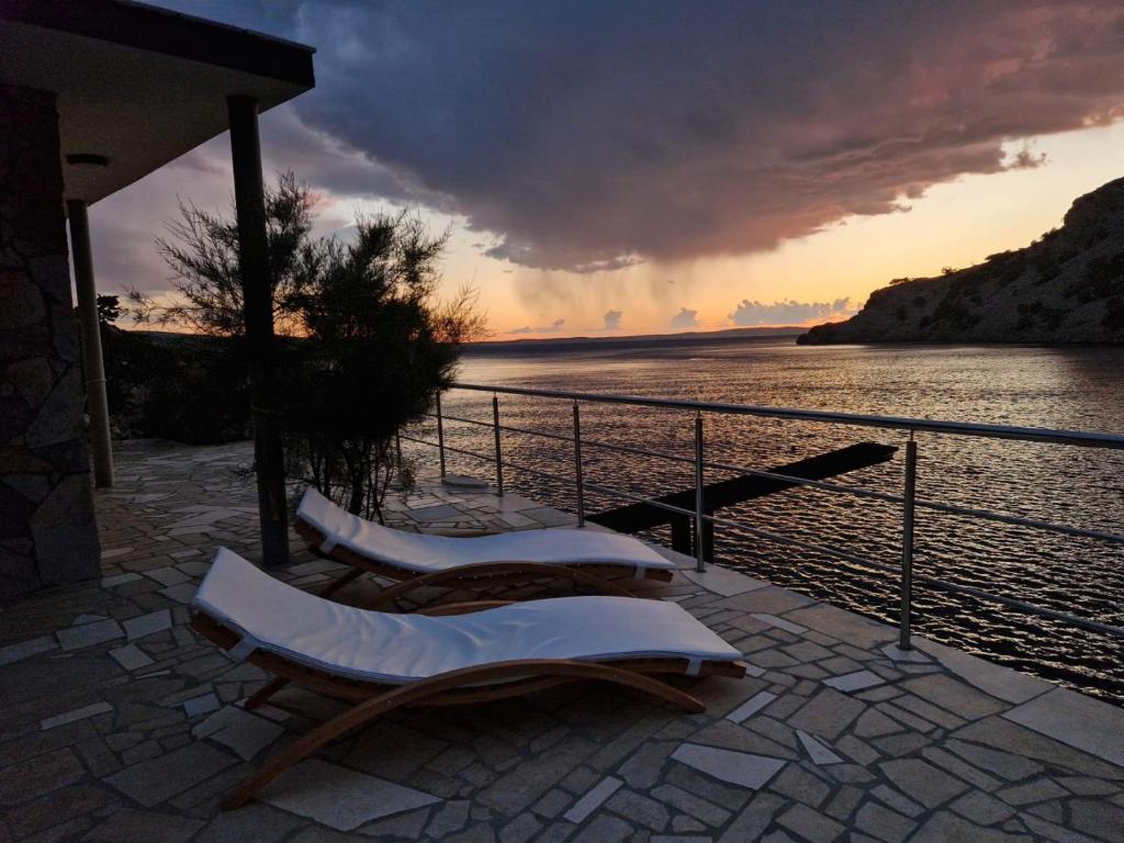 two chairs sitting on a patio near a body of water at Apartman Bačarije,Pag-Prizna in Seline