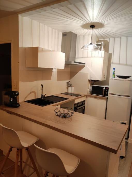 une cuisine avec des placards blancs et un comptoir avec des chaises dans l'établissement Appartement studio cosy centre avec place de parking, à Lorient