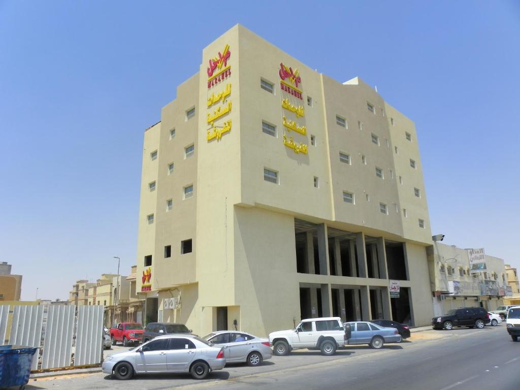 un grande edificio con auto parcheggiate in un parcheggio di مراحل للشقق المخدومة الخرج 2 ad Al Kharj