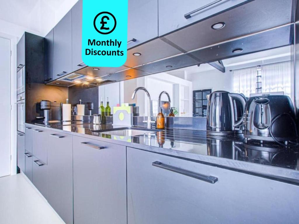 a large kitchen with white cabinets and stainless steel appliances at Popular 1BR Apartment Close to Queens Park TUBE with SUPER FAST INTERNET in London