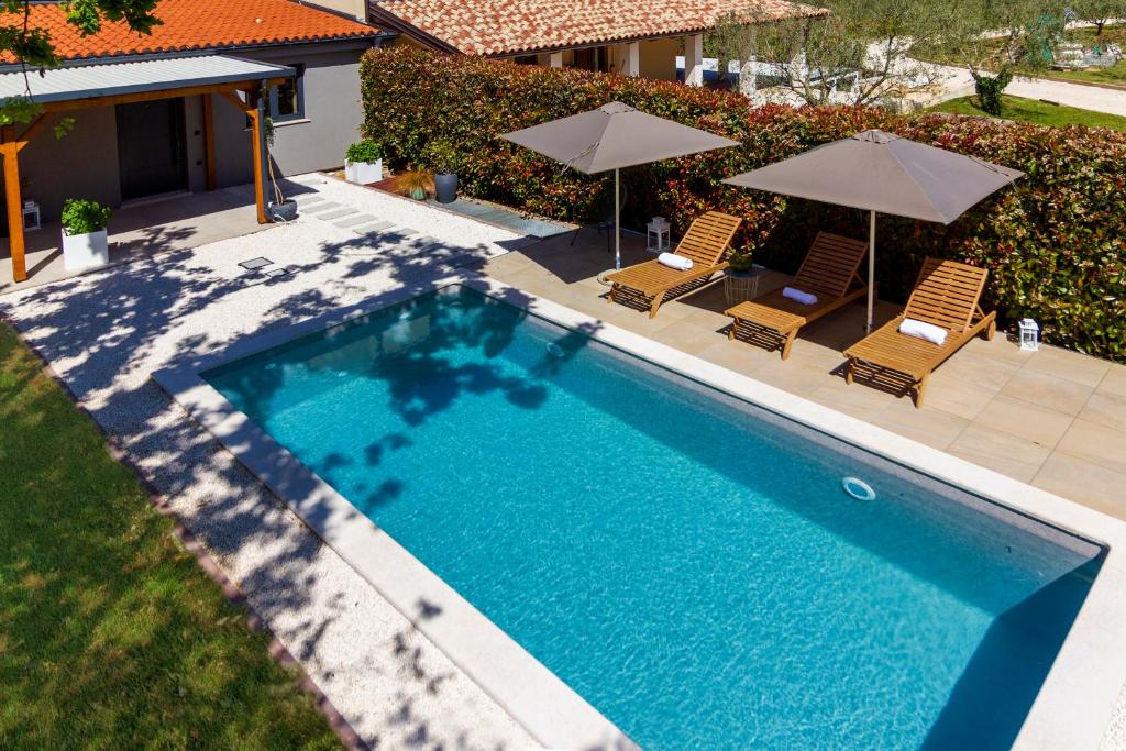 a swimming pool with two lawn chairs and umbrellas at Garden House Rovinj in Rovinj