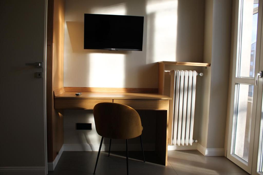 einen Schreibtisch mit einem TV und einem Stuhl in einem Zimmer in der Unterkunft Casa Ferrara J STADIUM by ConfirentHouse in Turin
