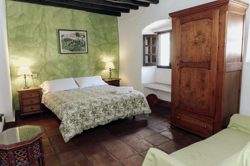 1 dormitorio con 1 cama y armario de madera en Casa Anon, en Jimena de la Frontera