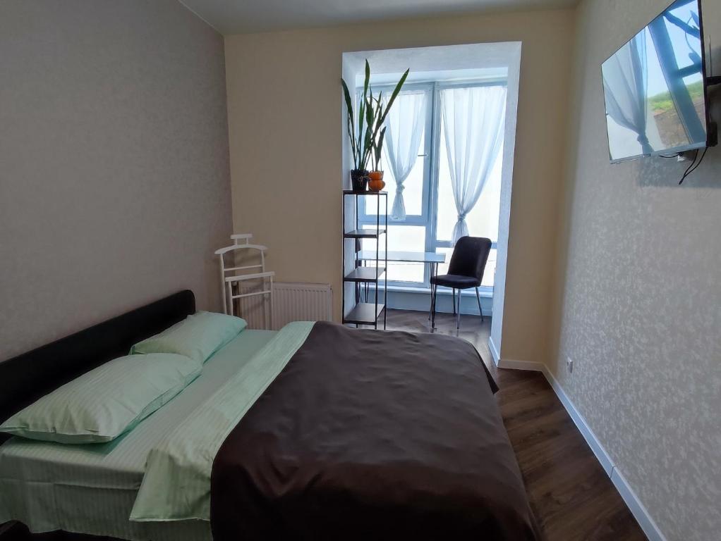 Schlafzimmer mit einem Bett, einem Tisch und einem Fenster in der Unterkunft Апартаменти в центрі Хмельницького (біля ТРЦ ЛибідьПлаза) in Chmelnyzkyj