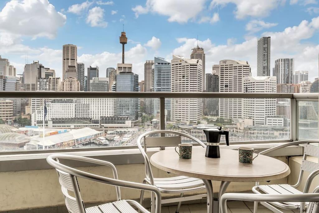 a table and chairs on a balcony with a view of a city at DREAM HARBOUR VIEW 2 BRM // GYM, POOL and PARKING in Sydney