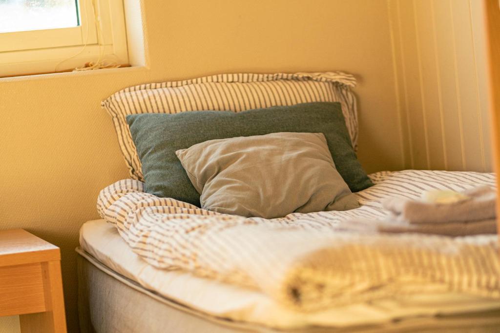 uma cama não feita com uma almofada e uma janela em Fjellheim Kurs- og Misjonssenter em Tromsø