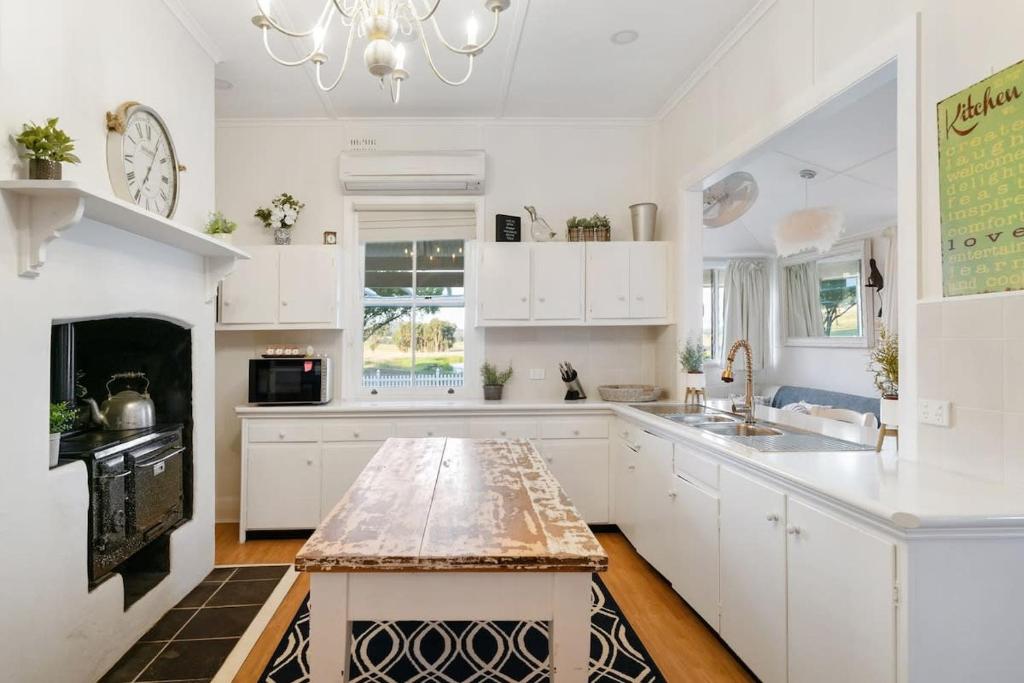 a kitchen with white cabinets and a marble counter top at Janie's Cottage - Secluded Wine Country Home in Broke