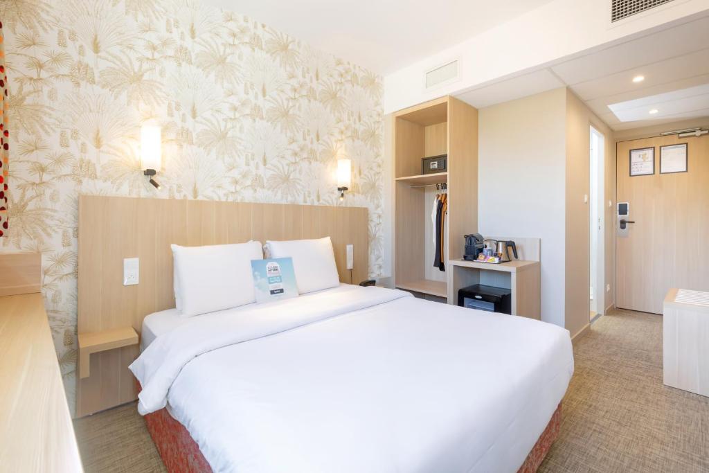 uma grande cama branca num quarto de hotel em Kyriad Avignon - Palais des Papes em Avignon