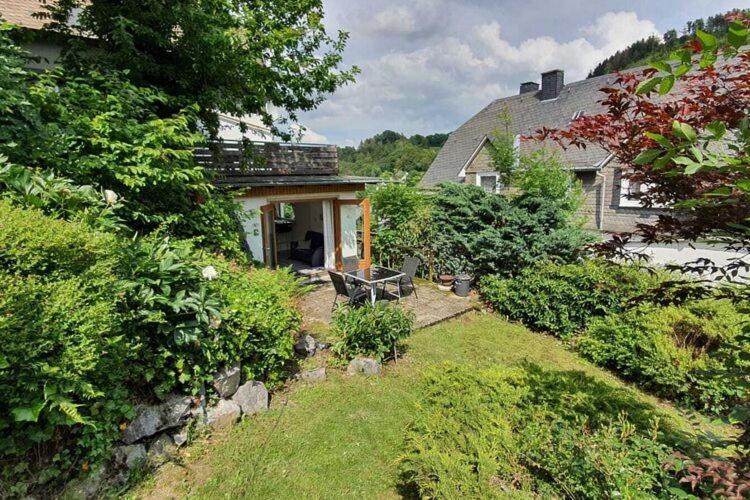 une maison dotée d'une cour avec un banc devant elle dans l'établissement Modern apartment near Willingen with private terrace and use of garden, à Willingen