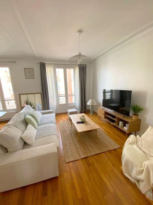ein Wohnzimmer mit einem weißen Sofa und einem TV in der Unterkunft Profitez de la golden hour depuis Levallois ! in Levallois-Perret