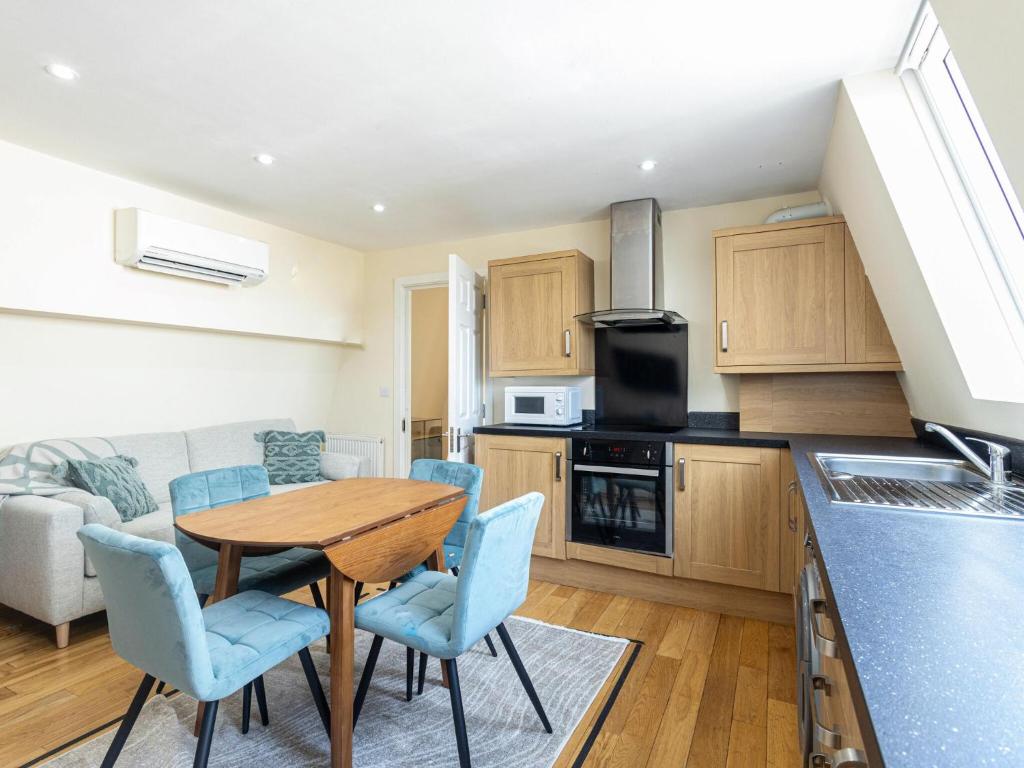 a kitchen with a wooden table and blue chairs at Family-Friendly 3-Bedroom Sojo Stay in London in London