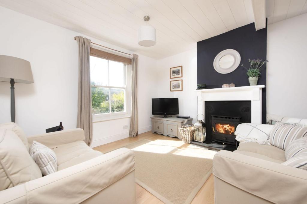 a living room with white furniture and a fireplace at Rutherglen in Porthallow