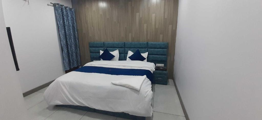 un letto blu e bianco in una piccola stanza di OYO HOTEL BLISS a Ludhiana