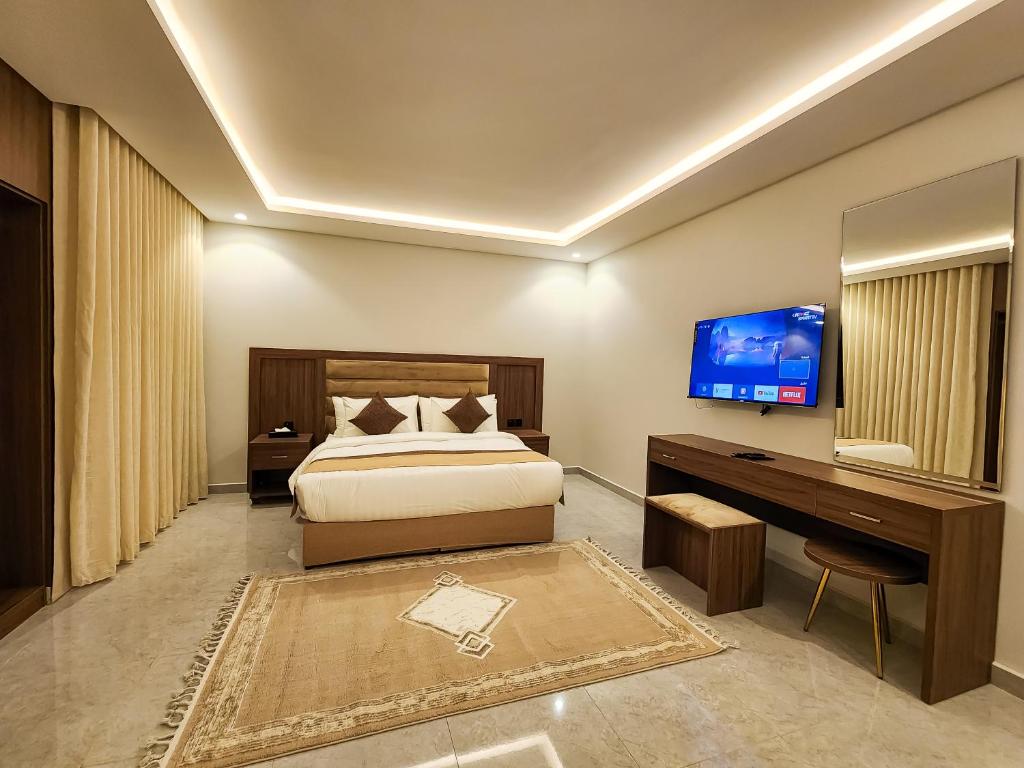 a bedroom with a bed and a desk and a television at Olaya Residence in Riyadh