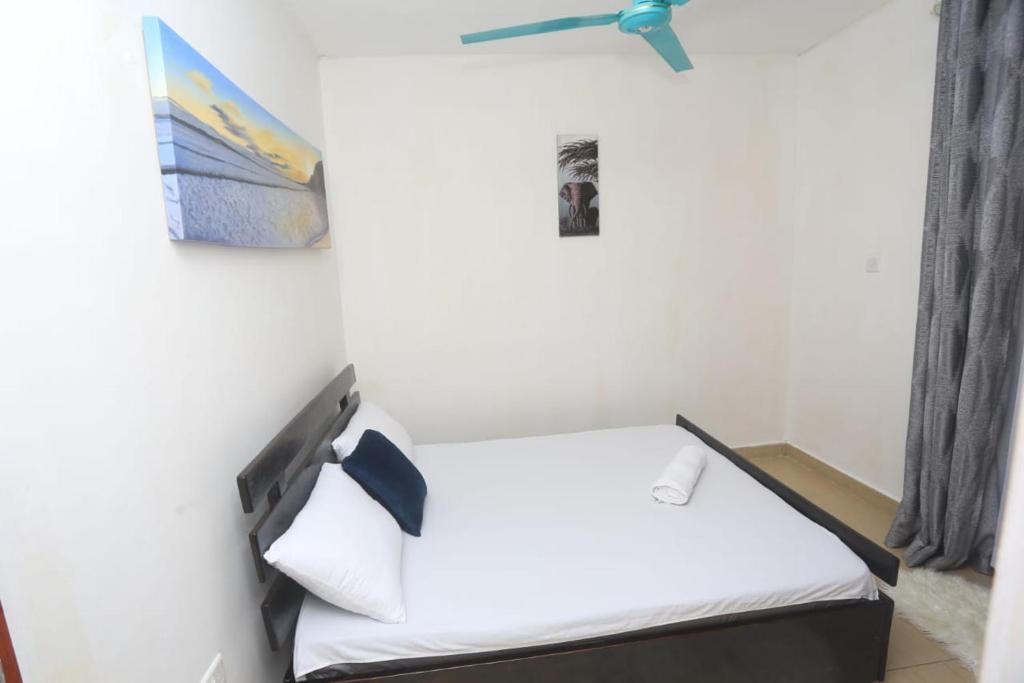 モンバサにあるOne bedroom fully furnished apartment at bamburiのベッド1台、天井ファンが備わる小さな客室です。