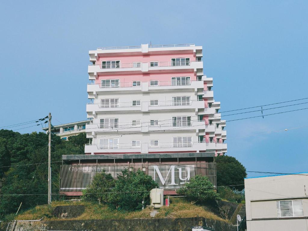 ein großes rosafarbenes Gebäude mit einem Schild drauf in der Unterkunft Guest Living Mu Nanki Shirahama in Shirahama
