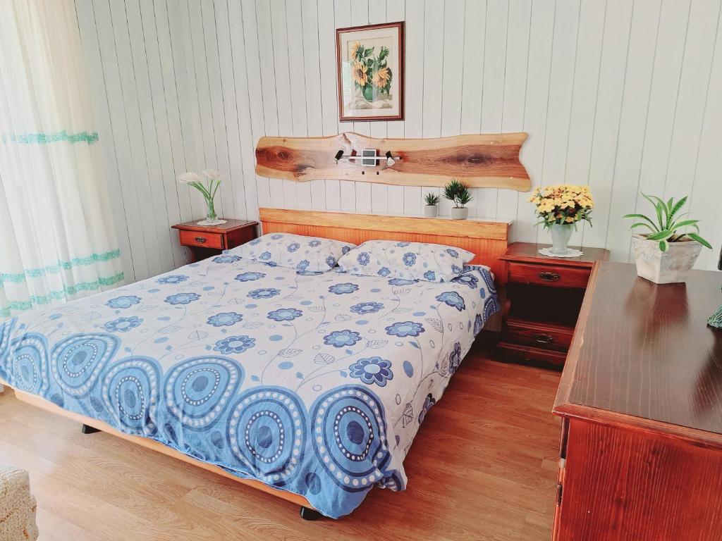 a bedroom with a bed with a blue and white comforter at Apartma Ferjan in Žaga