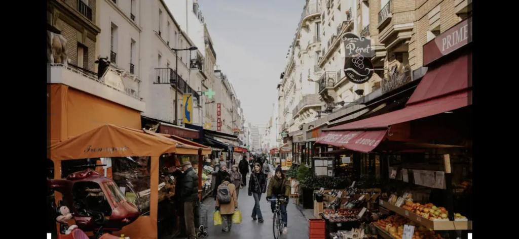 Un groupe de personnes marchant dans une rue avec des magasins dans l'établissement Petit studio, Rue Daguerre, à Paris