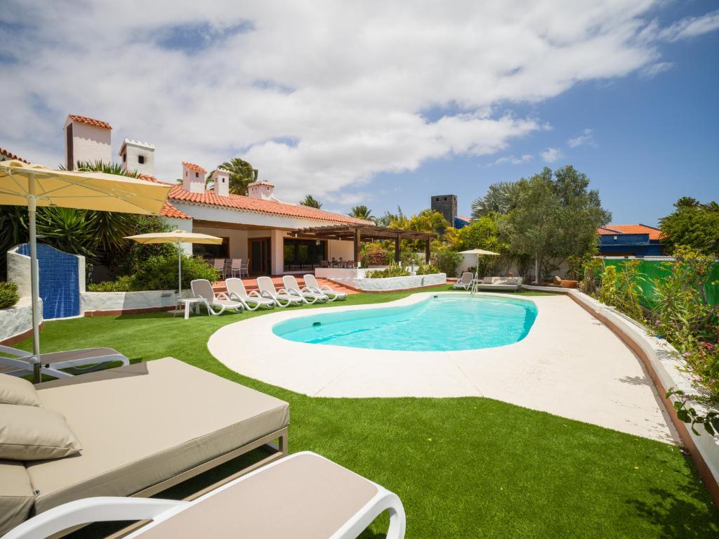 uma piscina num quintal com cadeiras e uma casa em CASA GRAN CANARIA - Gran Canaria Stays em Maspalomas