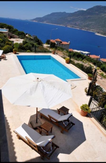 a swimming pool with two chairs and an umbrella at Bella Vista, Kaş Antalya in Kaş