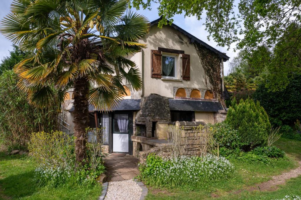 an old house with a palm tree in front of it at Jardins de la Cantine -l'entre deux in Locminé