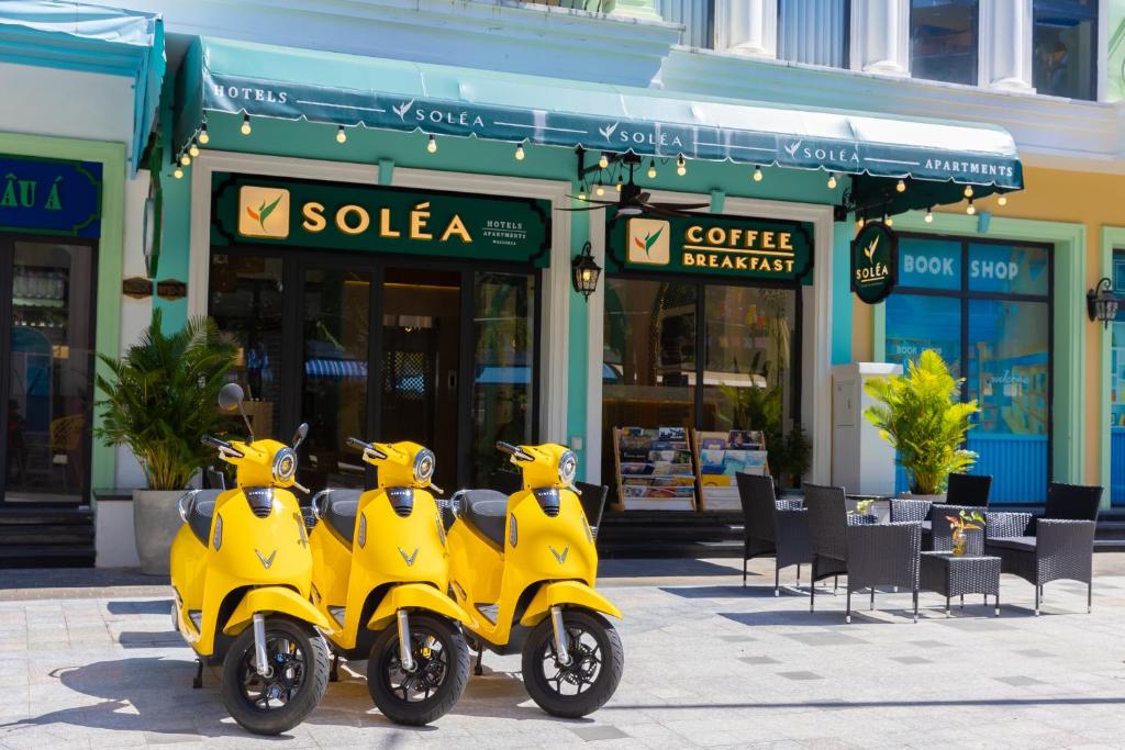 due scooter gialli parcheggiati di fronte a un negozio di SOLÉA Hotel GrandWorld Phu Quoc a Phu Quoc