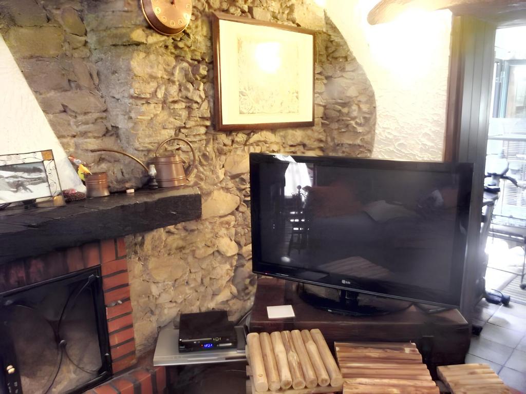 ein Wohnzimmer mit einem TV und einem Kamin in der Unterkunft 2 bedrooms house with sea view furnished terrace and wifi at Castelmola 5 km away from the beach in Castelmola