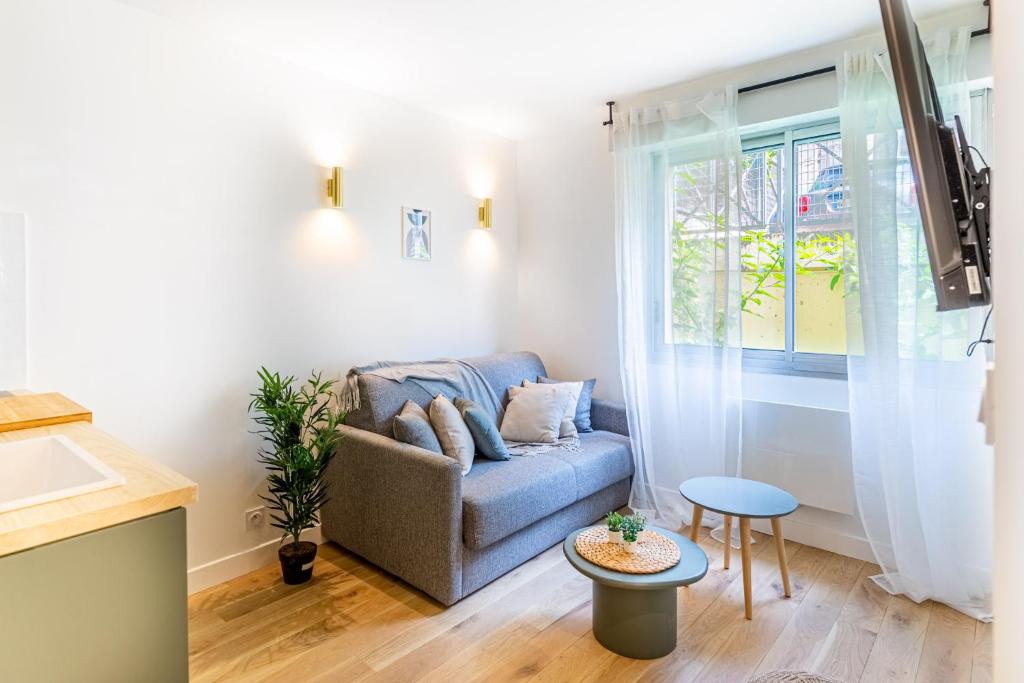 un salon avec un canapé et une fenêtre dans l'établissement Lavie Maison Equipped Studio, à Bordeaux