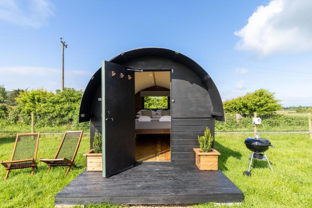 a black dome house with a bed in a field at The Piglets 3 in Yarmouth
