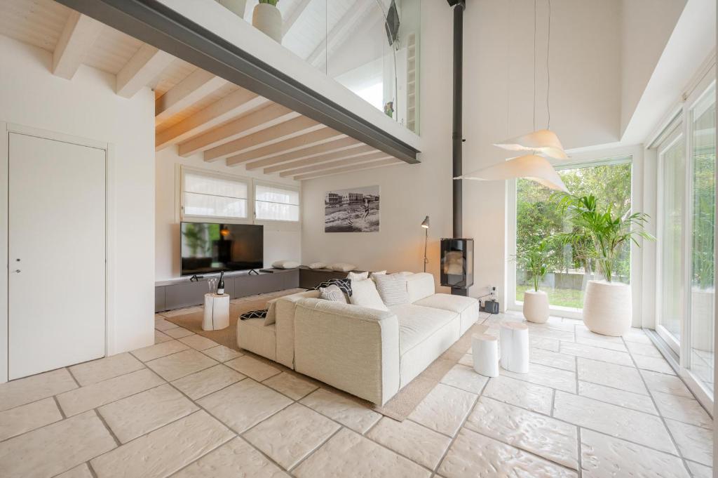 a living room with a white couch and a tv at Jesolo Beach Villa in Lido di Jesolo