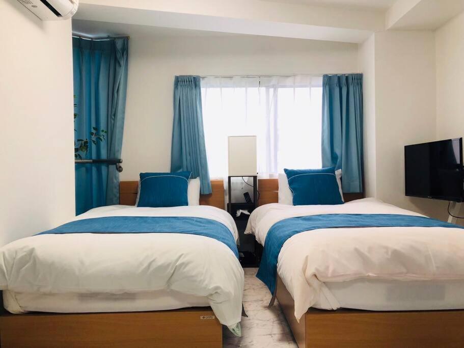2 camas en una habitación con cortinas azules en シティマインド京町802, en Osaka