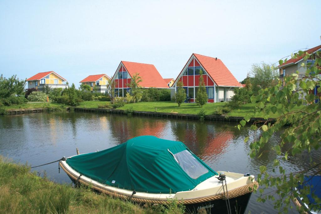 un barco con una lona en el agua junto a las casas en Summio Villapark Schildmeer, en Steendam