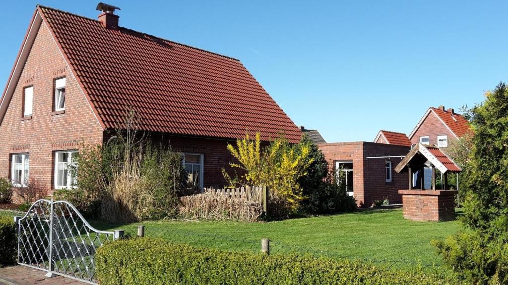 una casa in mattoni con tetto rosso di Freistehendes Haus mit großem, eingezäunten Garten, Sauna, Kamin a Krummhörn