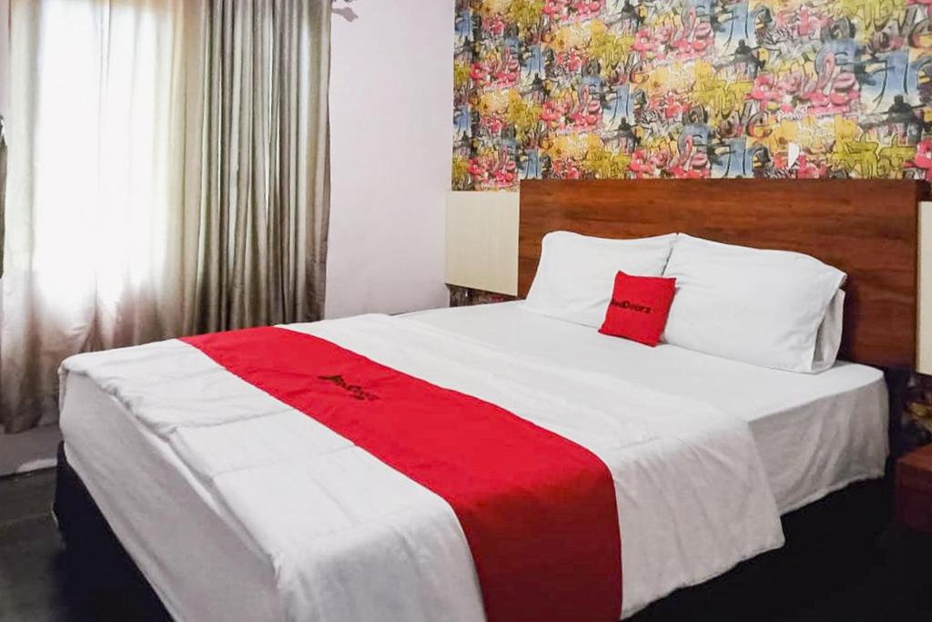 a bedroom with a large bed with a red and white blanket at RedDoorz at Pantai Panjang Bengkulu 2 in Bengkulu